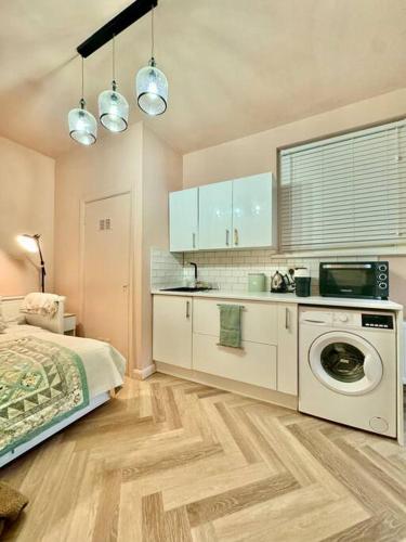 a bedroom with a bed and a kitchen with a washing machine at The Studio at Athol House in London