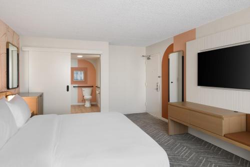 a hotel room with a bed and a flat screen tv at The Ambassador of Waikiki, Tapestry Collection by Hilton in Honolulu