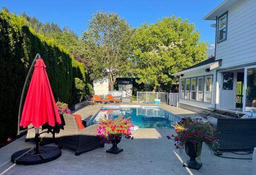 a backyard with a pool and an umbrella and flowers at WHITEWATER COTTAGE in Chilliwack