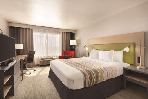 a hotel room with a bed and a flat screen tv at Country Inn & Suites by Radisson, Fresno North, CA in Fresno
