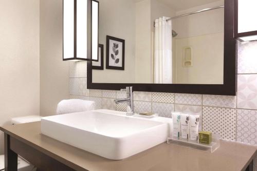 y baño con lavabo blanco y espejo. en Country Inn & Suites by Radisson, Fresno North, CA en Fresno