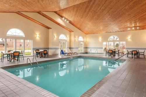 einen Pool in einem Hotel mit Tischen und Stühlen in der Unterkunft Country Inn & Suites by Radisson, Ames, IA in Ames