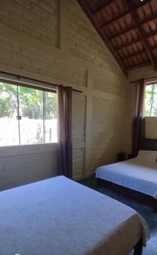 a bedroom with two beds and a large window at Chalé da Serra in Cavalcante