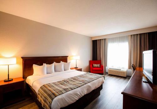 Habitación de hotel con cama y silla roja en Country Inn & Suites by Radisson, Wilson, NC, en Wilson