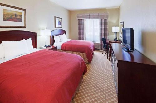 a hotel room with two beds and a flat screen tv at Country Inn & Suites by Radisson, Tulsa, OK in Tulsa