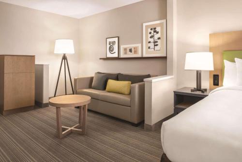 une chambre d'hôtel avec un lit et un canapé dans l'établissement Country Inn & Suites by Radisson, Dayton South, OH, à Dayton
