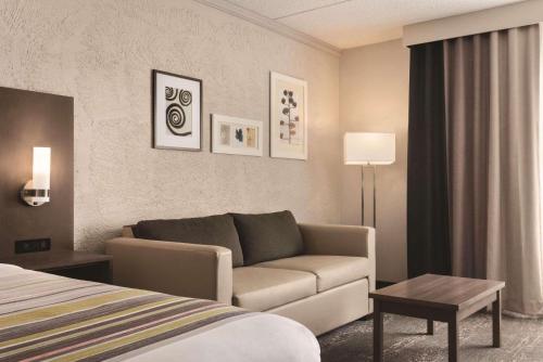 a hotel room with a couch and a bed at Country Inn & Suites by Radisson, Mt Pleasant-Racine West, WI in Sturtevant