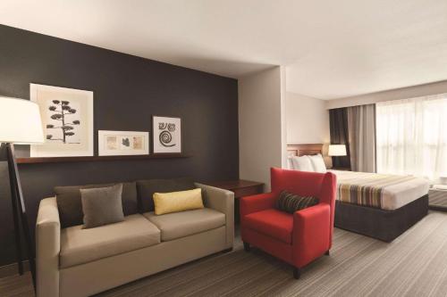 Country Inn & Suites by Radisson, Bentonville South - Rogers, AR في روجرز: غرفة في الفندق مع أريكة وسرير