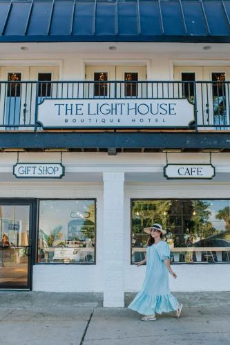 a woman in a blue dress walking in front of a building at The Lighthouse Boutique Hotel in Port Isabel