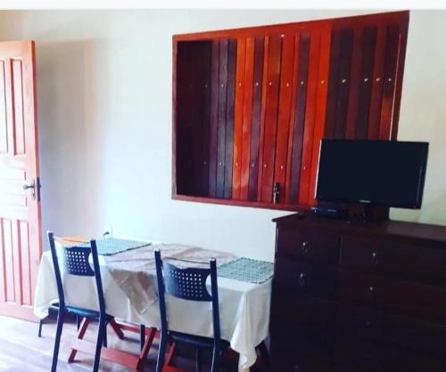 聖托梅－達斯萊特拉斯的住宿－CHALÉ ALPiNO MONTANHA MÁGICA，餐桌、两把椅子和电视