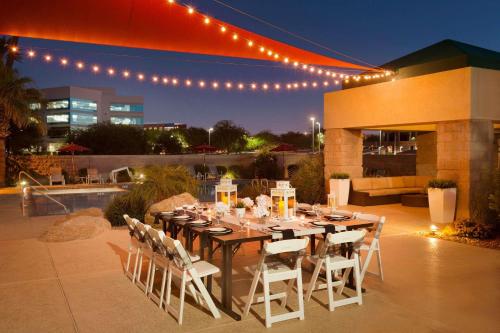 a dining table and chairs on a patio at night at Radisson Hotel Phoenix Airport in Phoenix