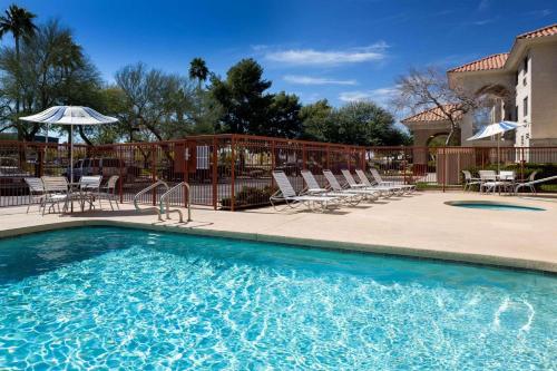 a swimming pool with chairs and an umbrella at Country Inn & Suites by Radisson, Phoenix Airport, AZ in Phoenix