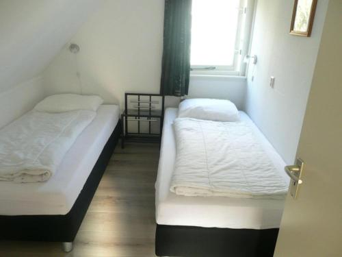 2 camas en una habitación pequeña con ventana en Holiday apartment Zonnewende 16, en Sint Maartensvlotbrug