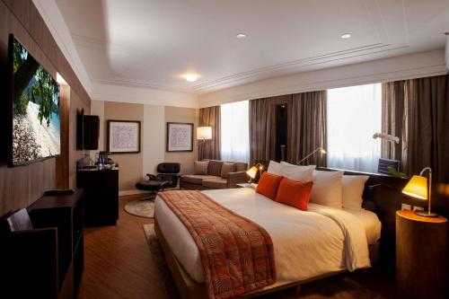 バルエリにあるRadisson Alphavilleのベッドとリビングルームが備わるホテルルームです。