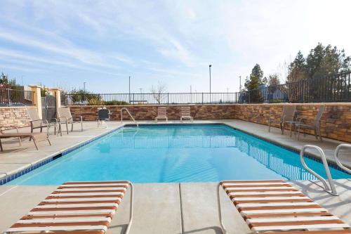 a swimming pool with lounge chairs next to a brick wall at Country Inn & Suites by Radisson, Dixon, CA - UC Davis Area in Dixon