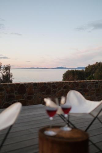 two glasses of red wine on a table near the water at Piermont Retreat in Swansea