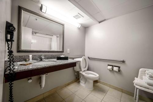 a bathroom with a toilet and a sink and a mirror at Country Inn & Suites by Radisson, Ontario at Ontario Mills, CA in Ontario
