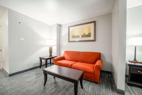a living room with an orange couch and a table at Country Inn & Suites by Radisson, Ontario at Ontario Mills, CA in Ontario