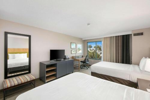 a hotel room with two beds and a desk with a mirror at Country Inn & Suites by Radisson, San Diego North, CA in Mira Mesa