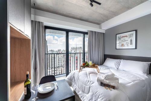 a bedroom with a bed and a window with a table at VN Ueno in Sao Paulo