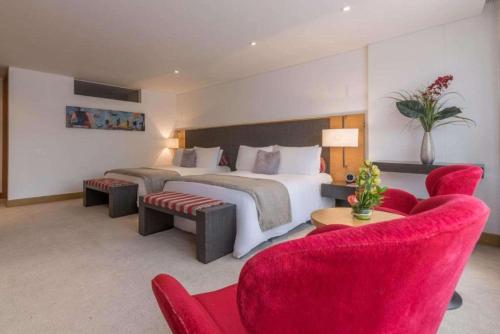 a bedroom with a large bed and red chairs at Faranda Collection Bogota, a member of Radisson Individuals in Bogotá