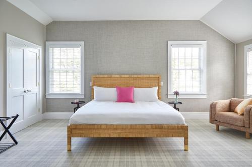 een slaapkamer met een bed met een roze kussen en een stoel bij The Kent Collection in Kent