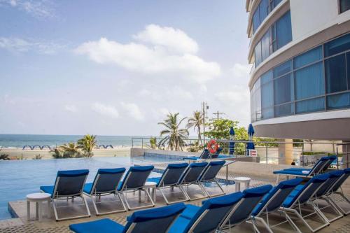 eine Gruppe von Stühlen, die um einen Tisch neben dem Meer herum sitzen in der Unterkunft Radisson Cartagena Ocean Pavillion Hotel in Cartagena de Indias