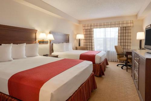 a hotel room with two beds and a television at Country Inn & Suites by Radisson, Calgary-Northeast in Calgary