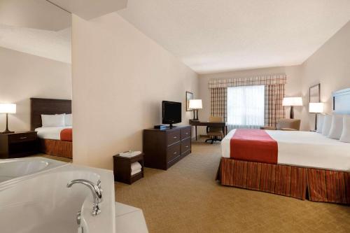 Country Inn & Suites by Radisson, Calgary-Northeast في كالغاري: غرفة فندقية بسريرين وحوض استحمام