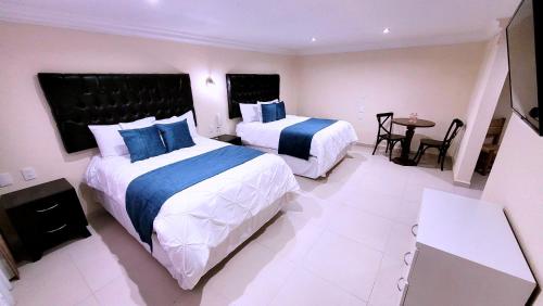 a hotel room with two beds and a table at Hotel Tierras Blancas in Valle de Bravo