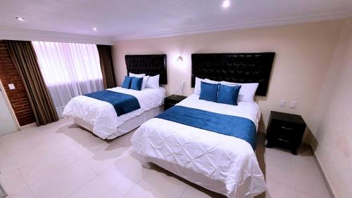 a hotel room with two beds with blue pillows at Hotel Tierras Blancas in Valle de Bravo