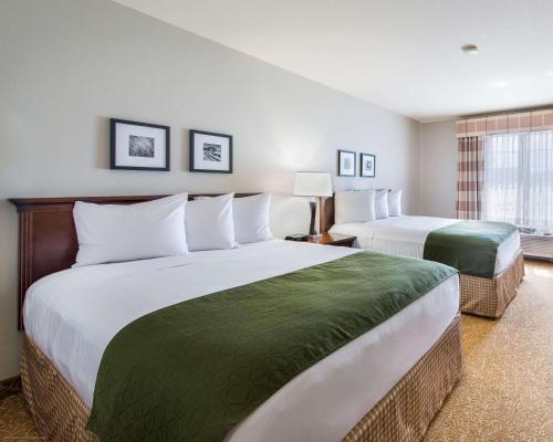 a hotel room with two beds and a window at Country Inn & Suites by Radisson, Greeley, CO in Greeley