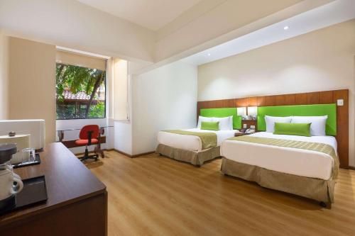 a hotel room with two beds and a television at Country Inn & Suites by Radisson, San Jose Aeropuerto, Costa Rica in San José