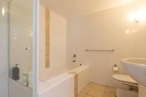 a bathroom with a tub and a toilet and a sink at 'Sage' at The Crest - Spacious ground floor apartment in Forster