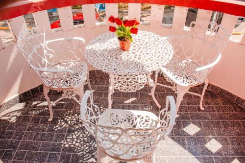 una mesa blanca y sillas con un jarrón de flores en Pousada Arco-Íris en Lambari