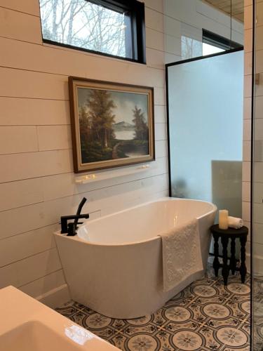 a bath tub in a bathroom with a painting on the wall at Le201chaletlactaureau in Saint-Michel-des-Saints