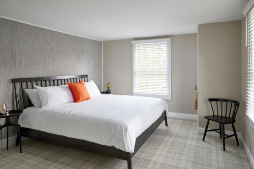 a bedroom with a large bed with an orange pillow at The Kent Collection - The Firefly Inn in Kent
