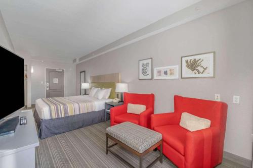 a hotel room with a bed and two red chairs at Country Inn & Suites by Radisson, Port Canaveral, FL in Cape Canaveral