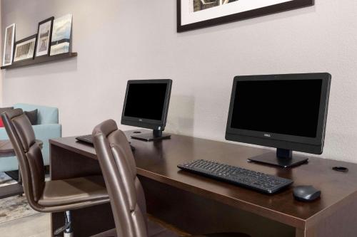 a desk with two computer monitors and a keyboard at Country Inn & Suites by Radisson, Port Canaveral, FL in Cape Canaveral