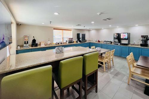 a large kitchen with blue cabinets and green chairs at Country Inn & Suites by Radisson, Panama City, FL in Panama City