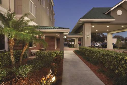 a house with a palm tree next to a sidewalk at Country Inn & Suites by Radisson, St Petersburg - Clearwater, FL in Pinellas Park