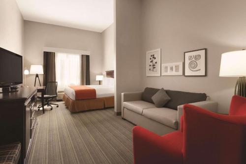a hotel room with a couch and a bed at Country Inn & Suites by Radisson, St Petersburg - Clearwater, FL in Pinellas Park