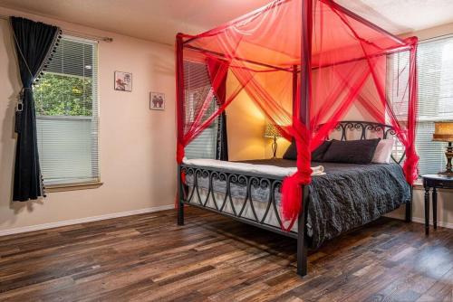 a bedroom with a canopy bed with red curtains at Alice- The Wonderland Experience in Salem