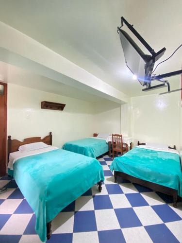 2 camas azules en una habitación con suelo a cuadros en Hospedaje el Poseidon, en Chachapoyas