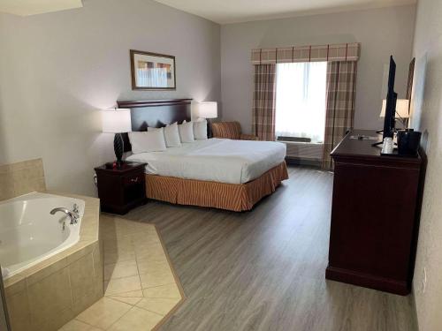 ジャクソンビルにあるCountry Inn & Suites by Radisson, Jacksonville West, FLのベッドとバスタブ付きのホテルルームです。