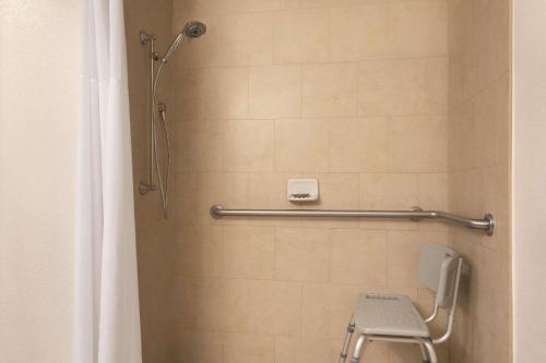 uma casa de banho com um chuveiro, um WC e uma cadeira. em Country Inn & Suites by Radisson, Bradenton-Lakewood-Ranch, FL em Bradenton