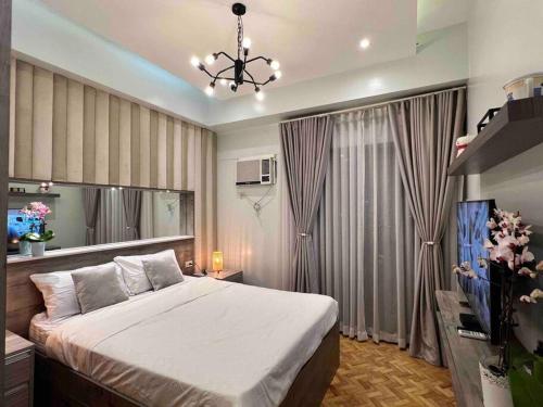 a bedroom with a large bed and a chandelier at Penthouse Condo Unit near Airport NAIA in Manila