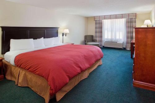 a hotel room with a large bed with a red blanket at Country Inn & Suites by Radisson, Hiram, GA in Hiram
