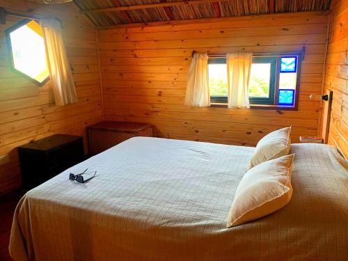 a bedroom with a bed in a wooden room at Nao Tem Fim in Punta Del Diablo