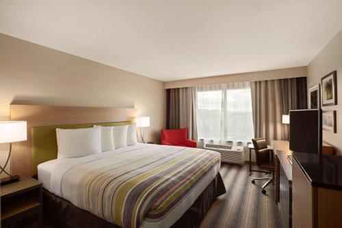 a hotel room with a bed and a red chair at Country Inn & Suites by Radisson, McDonough, GA in McDonough